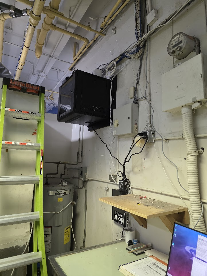 After: wall-mounted network cabinet installed in a utility room with cabling routed from the ceiling