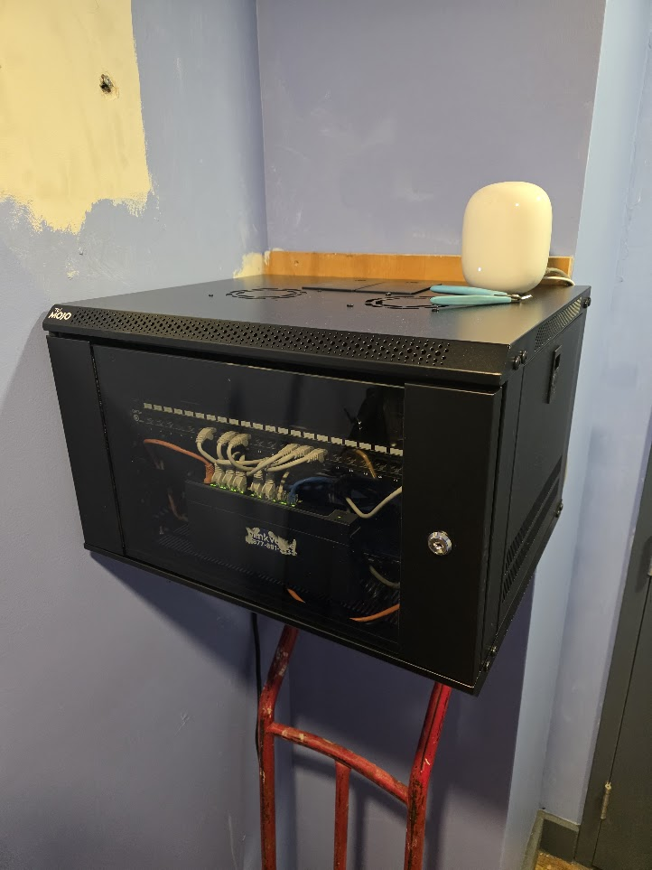 Wall-mounted network rack with patch panel, switch, and cabling installed on site